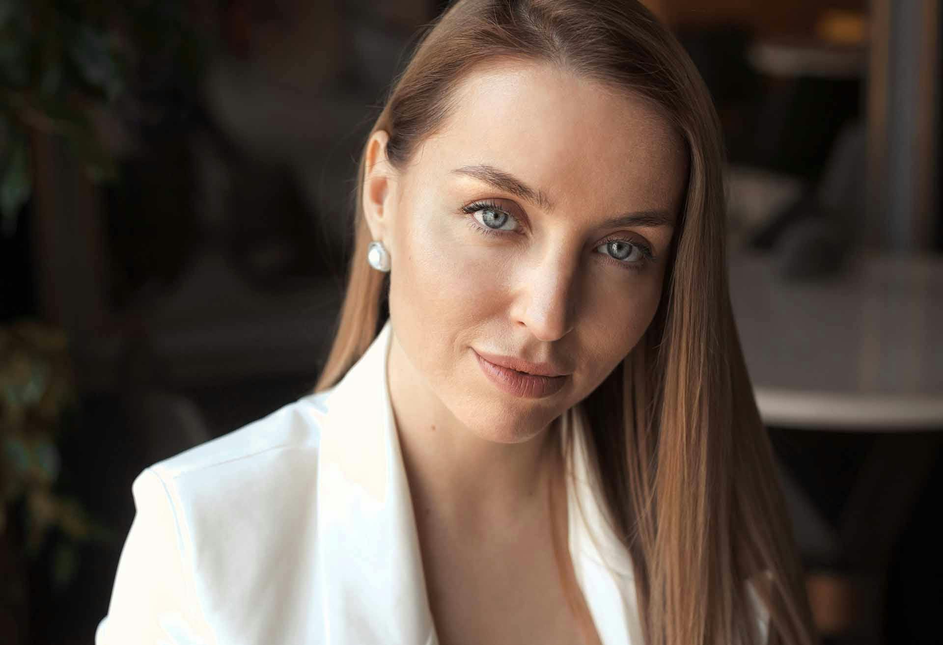 Close-up of a woman with a white top and white earrings
