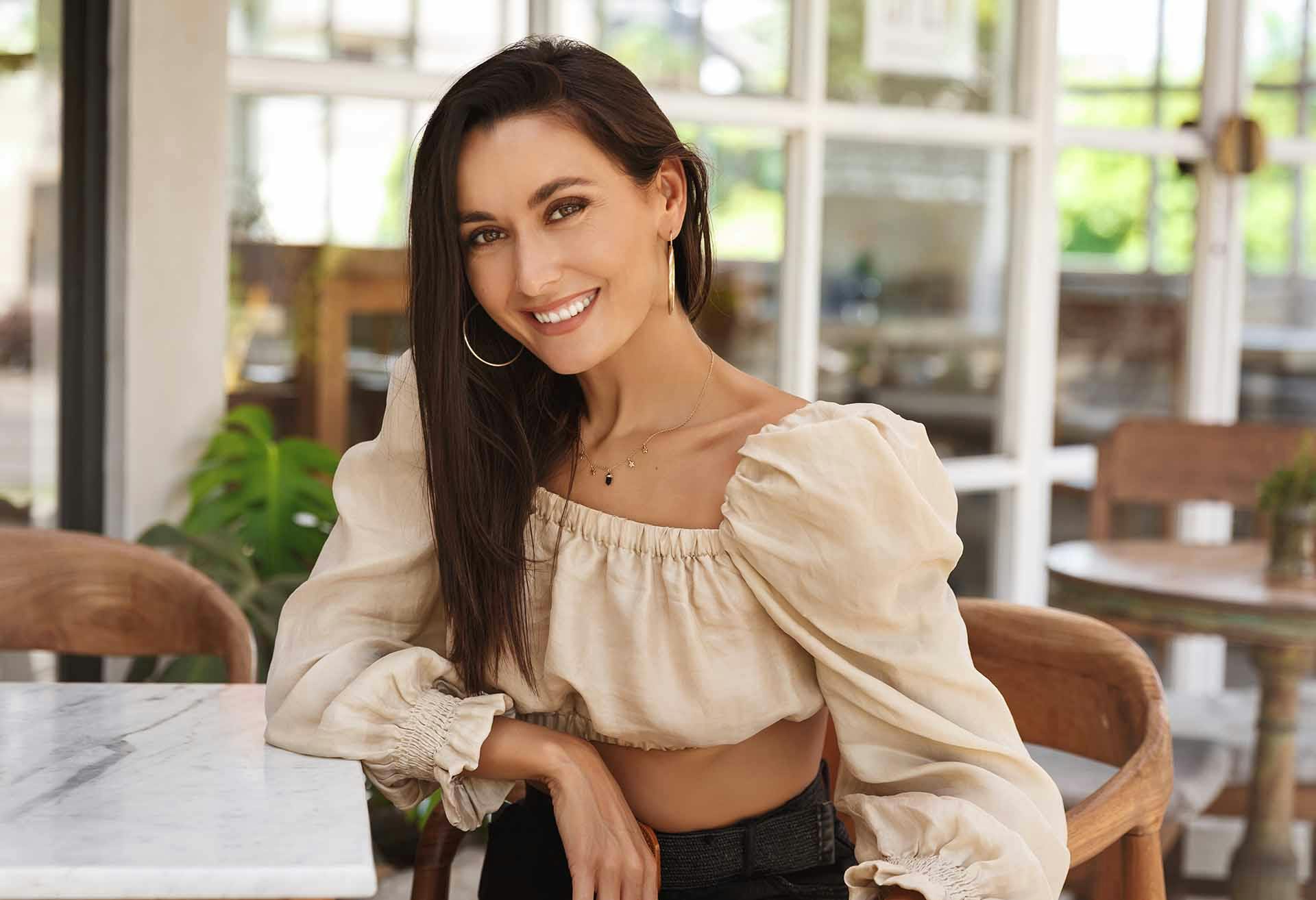 Woman with a poofy top and dark, straight hair smiling