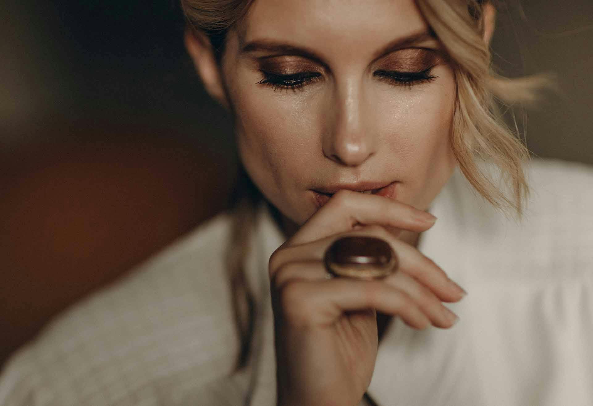 Woman with a finger against her lips, looking down