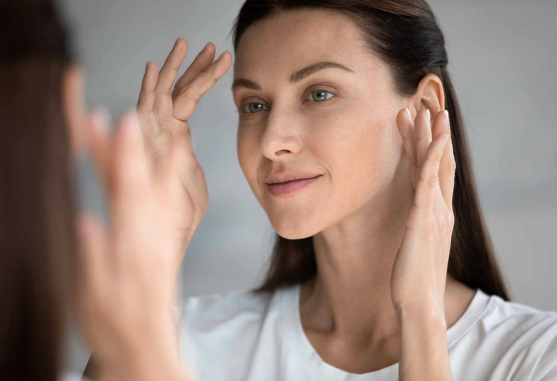 Woman looking at her face in the mirror