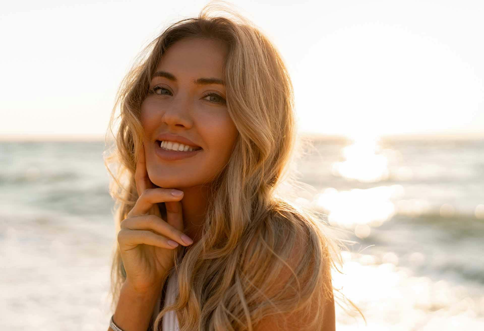 Woman with wavy blond hair smiling at the beach