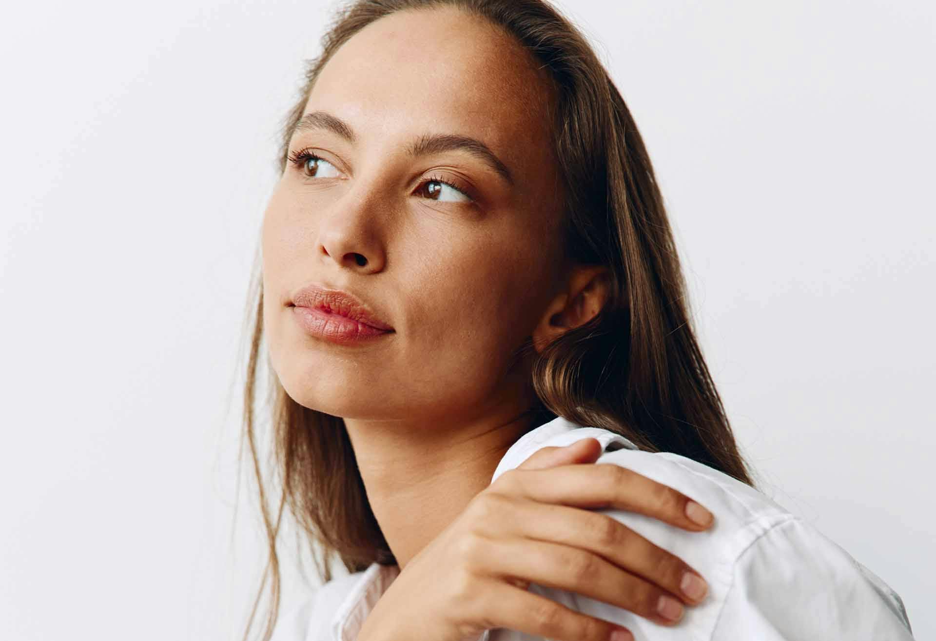 Woman with her hand on her shoulder, looking off to the side
