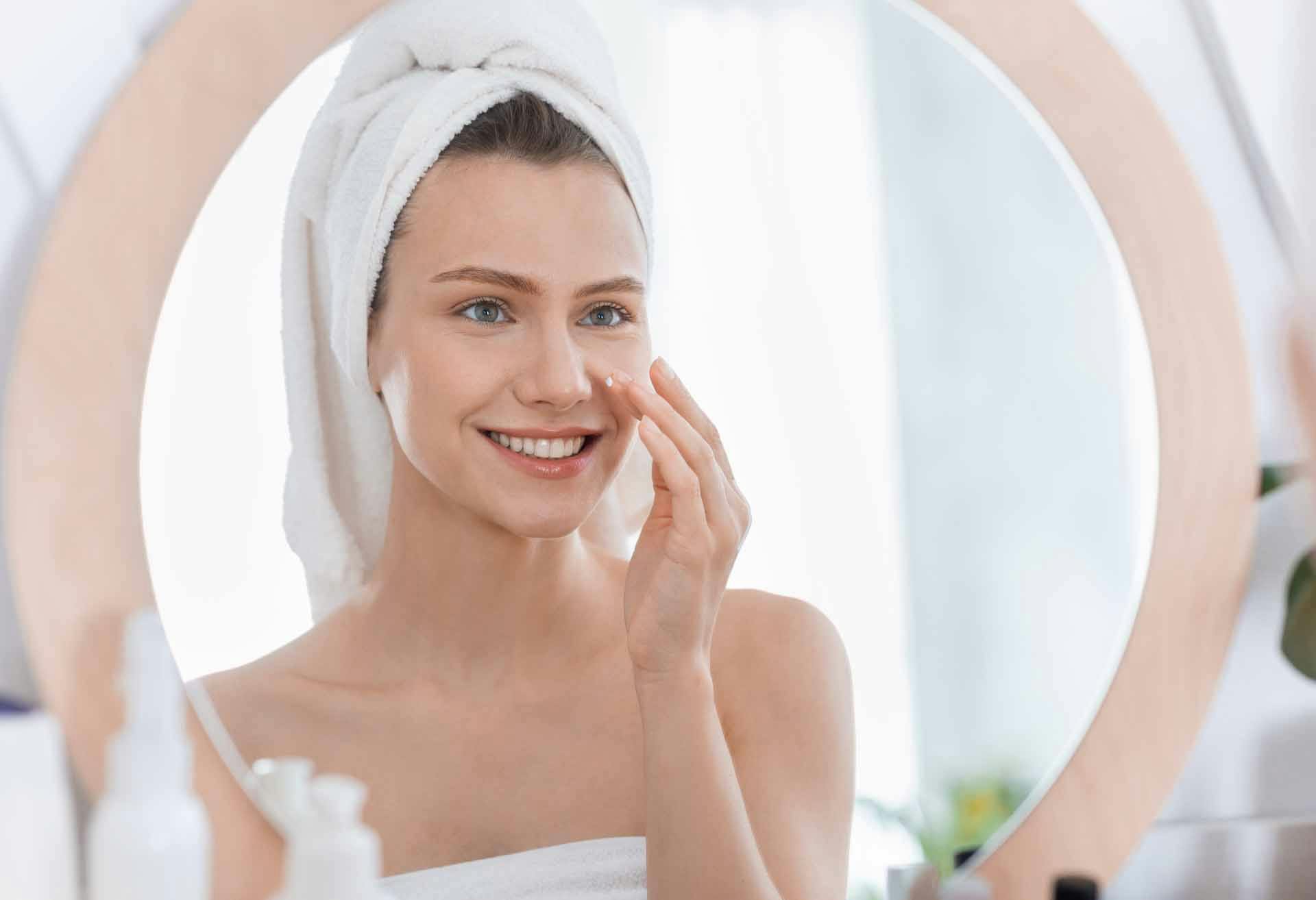 Woman with a hand to her face, looking in the mirror