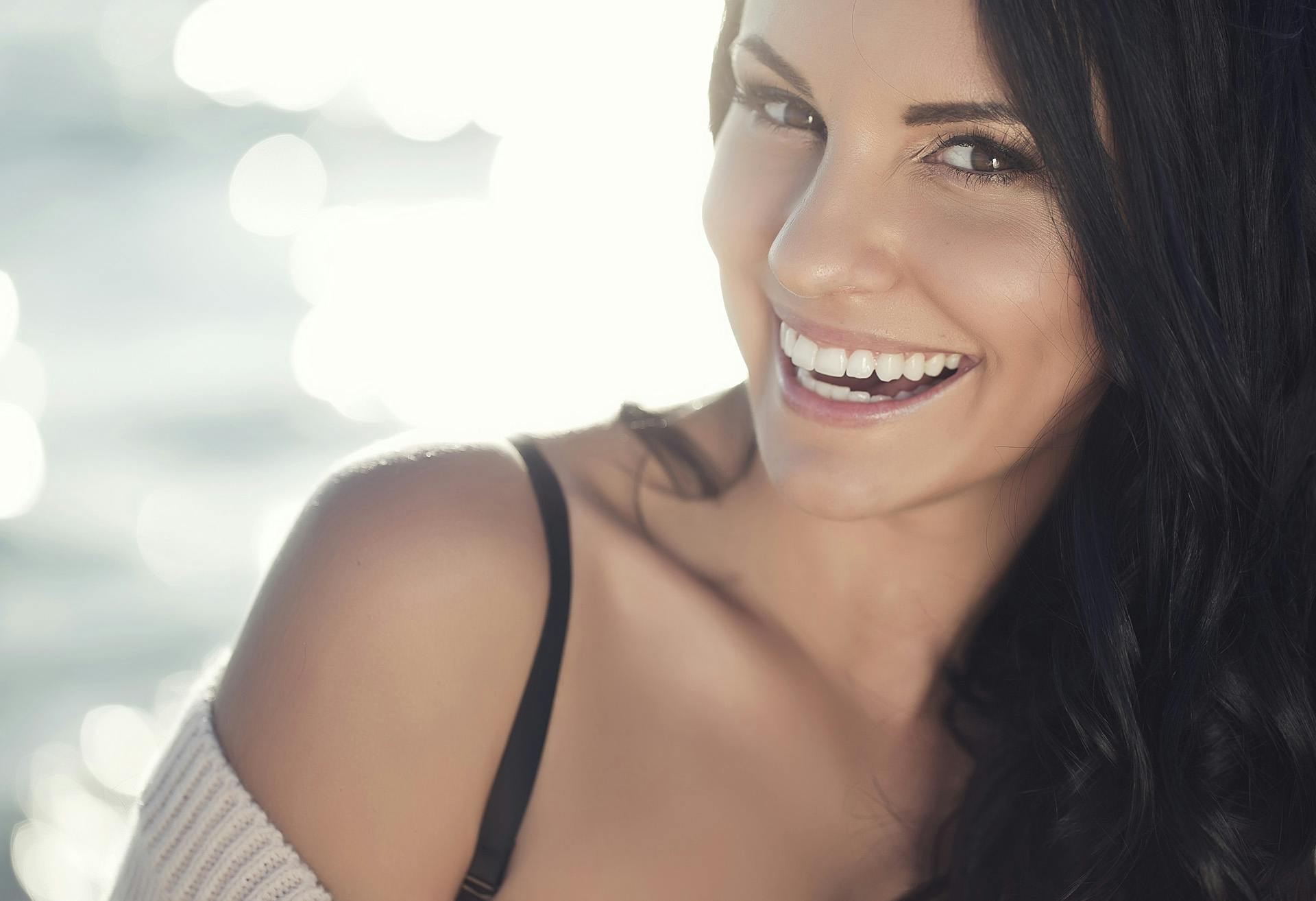 Woman smiling with a sweater pulled down her shoulder
