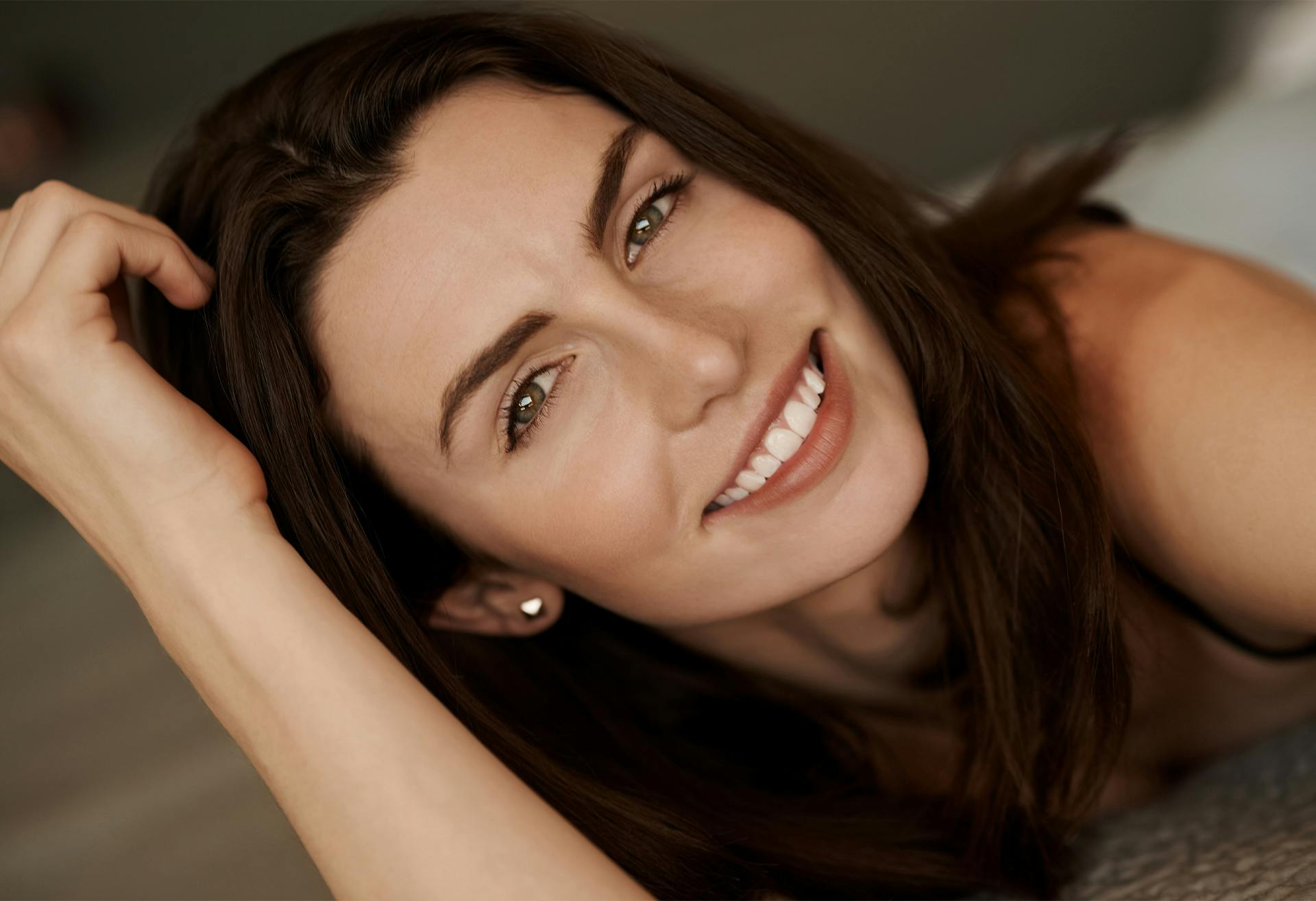 Angled shot of a woman smiling with her hand to her head