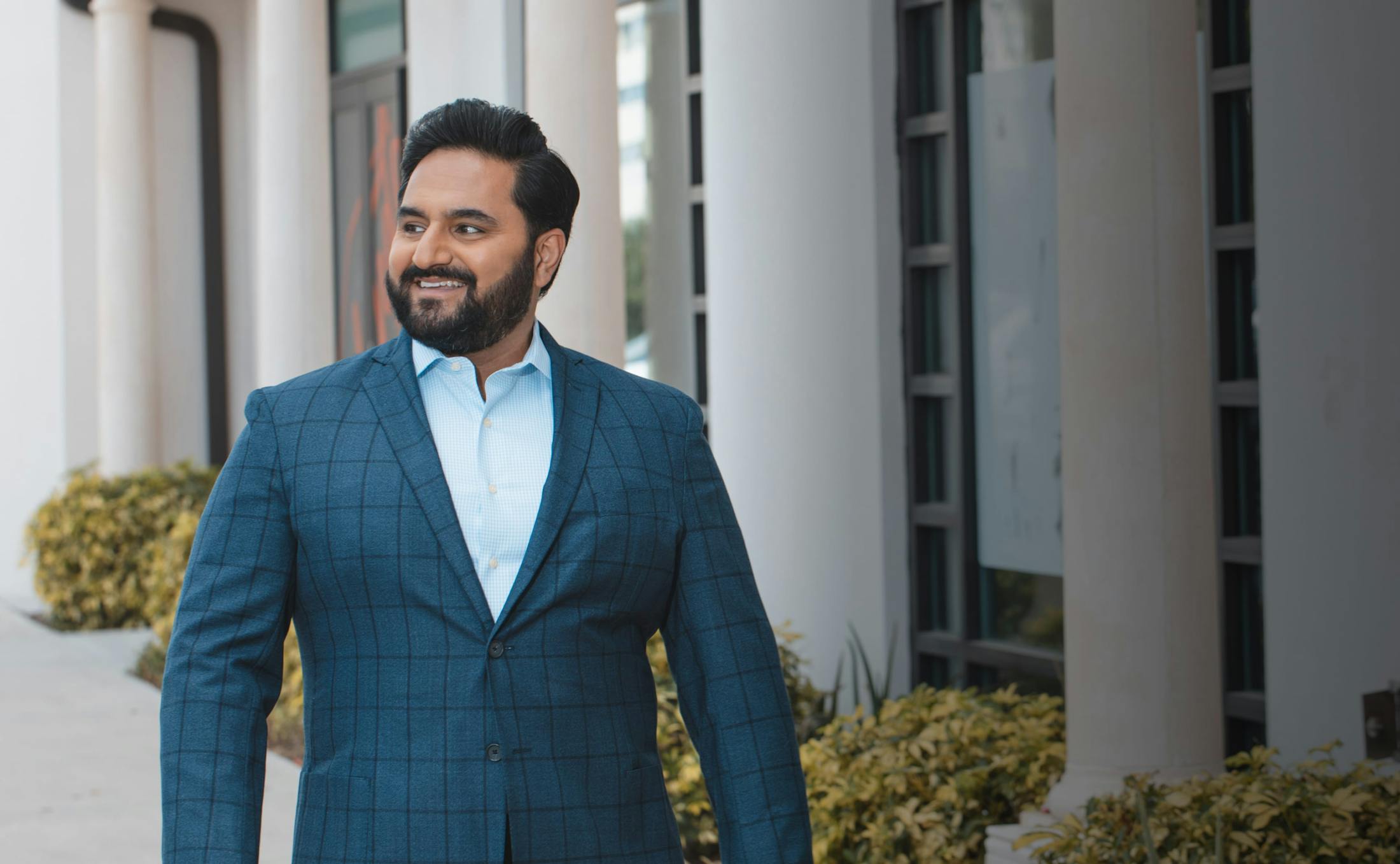 Doctor Sharma Wearing a Blue Suit and Smiling to the Side