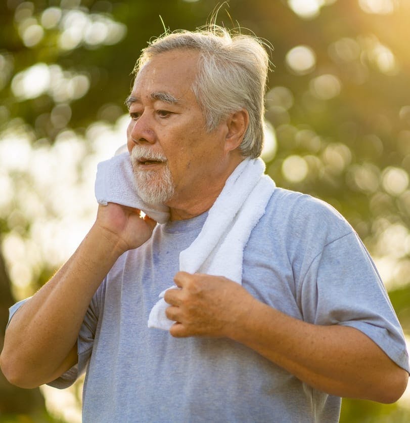 Man wiping face with towel outside