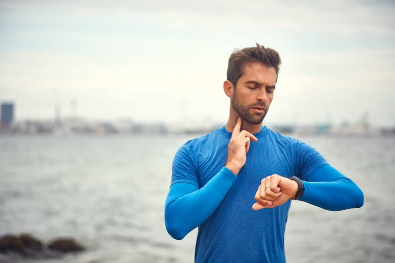 Athletic man checking pulse against watch