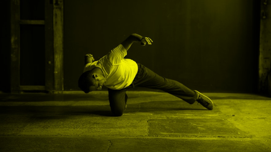 Person balanced on one bent knee, with the other leg straight out to the side, leaning forward bent from the waist as if about to overbalance.