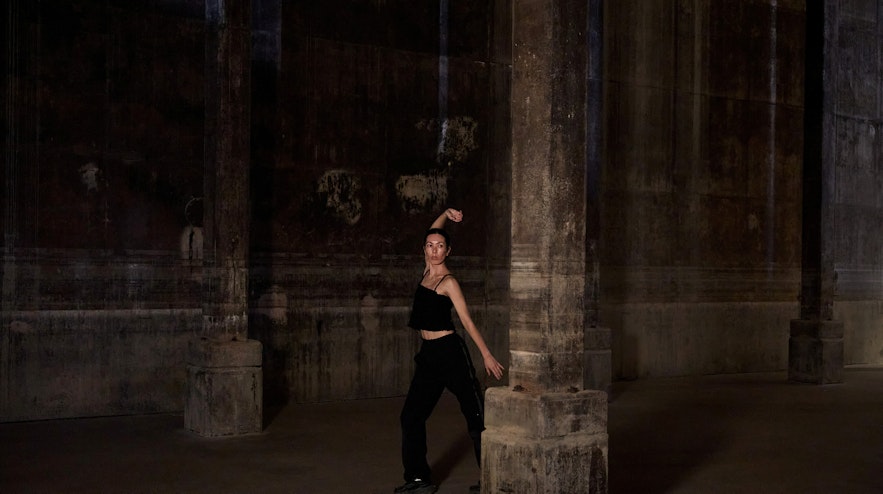A person stretching one arm above their head in a former World War 2 oil tank space