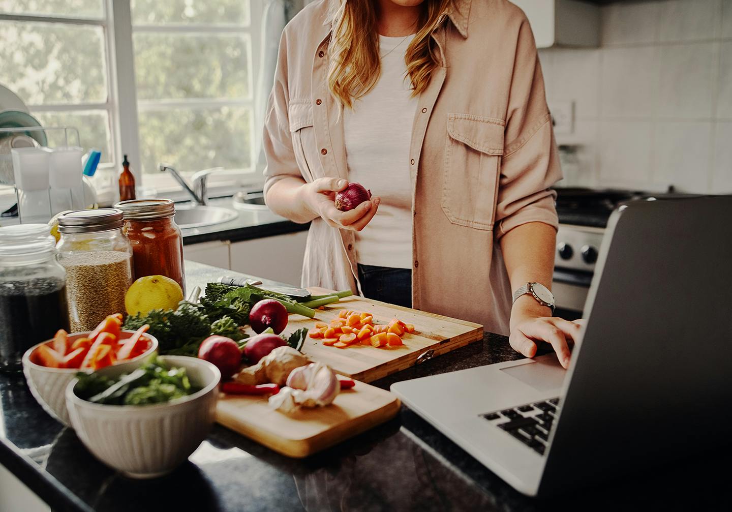 Woman preparing vegetables near laptop