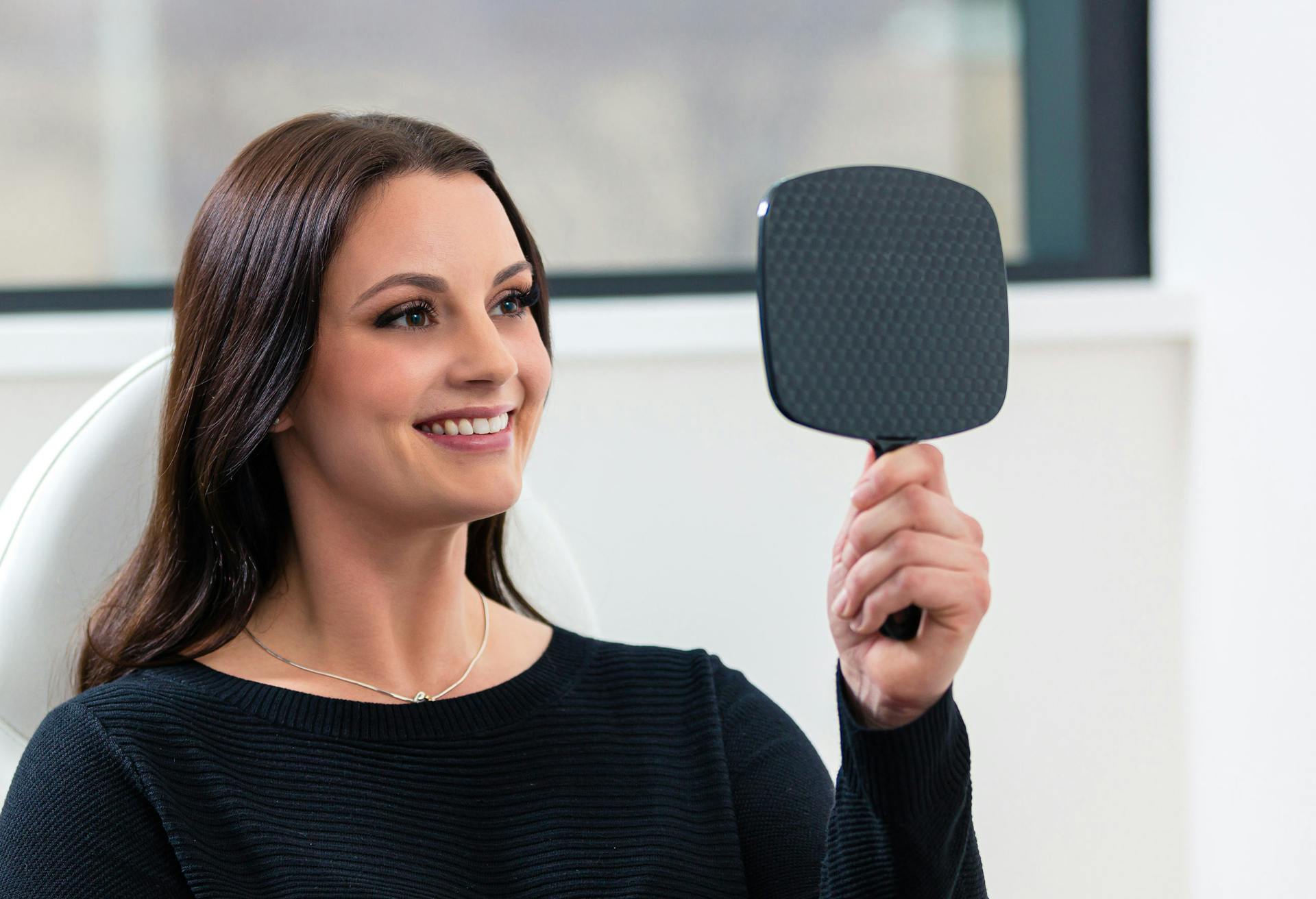 Woman looking in a hand-held mirror