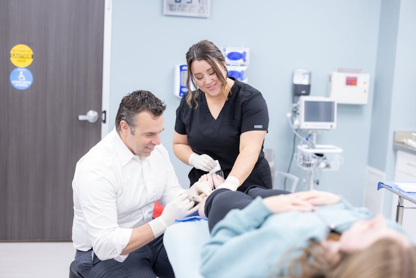 Male doctor and female nurse preparing patient for aesthetic procedure