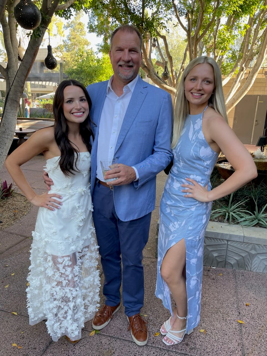 A man standing with 2 women in formal wear