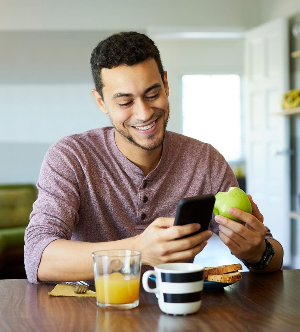 Man eating fruit while looking at phone