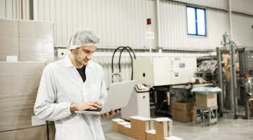 man using a laptop in a manufacturing facility