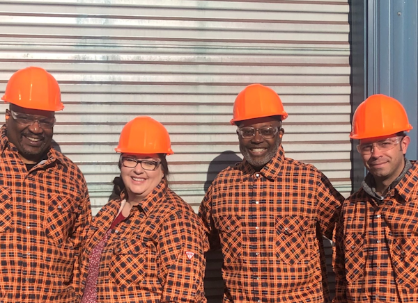 Smiling SafetyChain employees in hard hats at a customer facility
