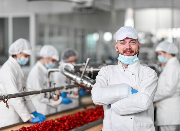 Manufacturing operator smiling with arms crossed on the factory floor
