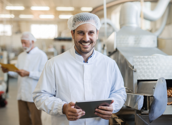 Manufacturing operator smiling with tablet.