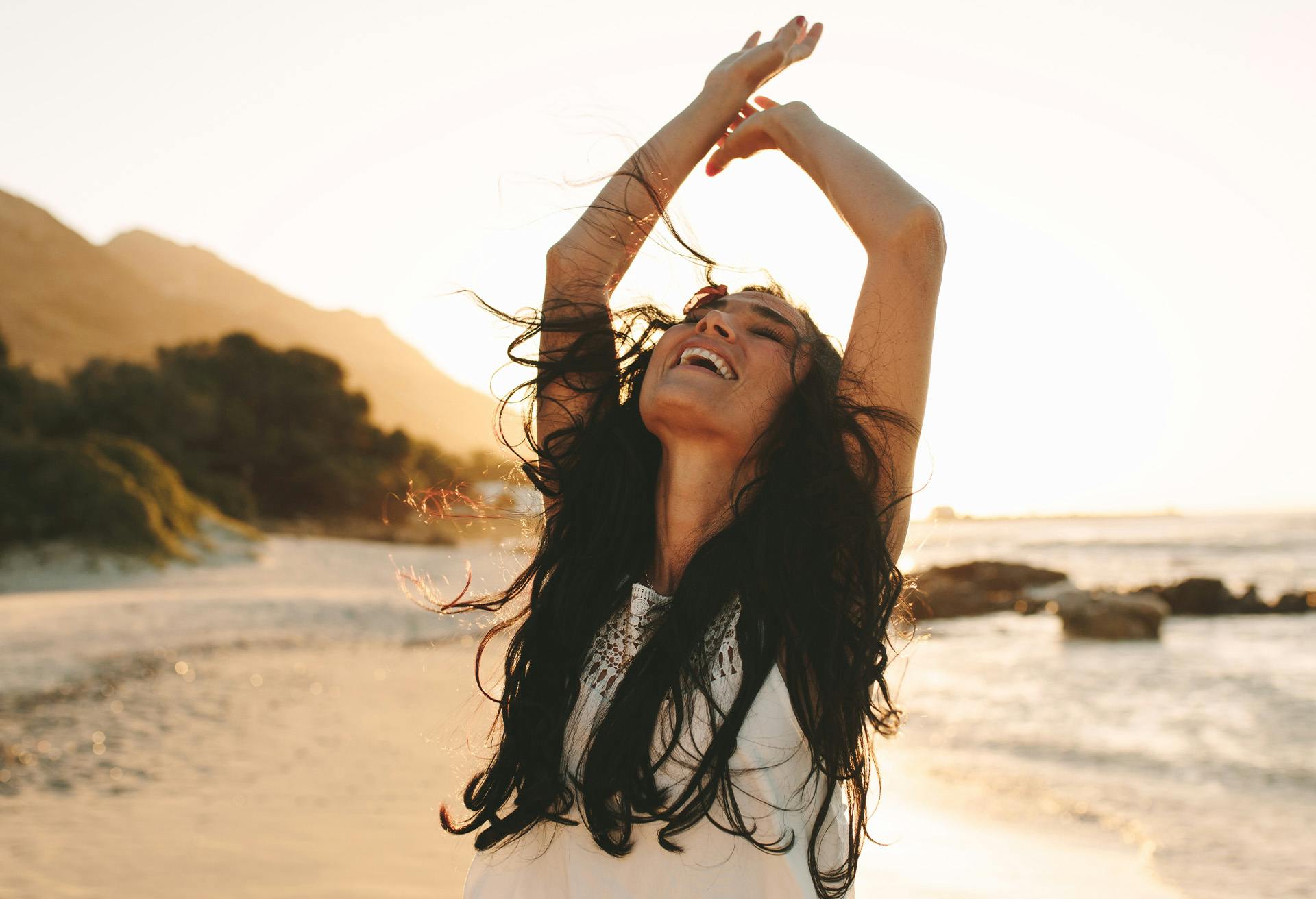 Woman at the beach with her arms in the air