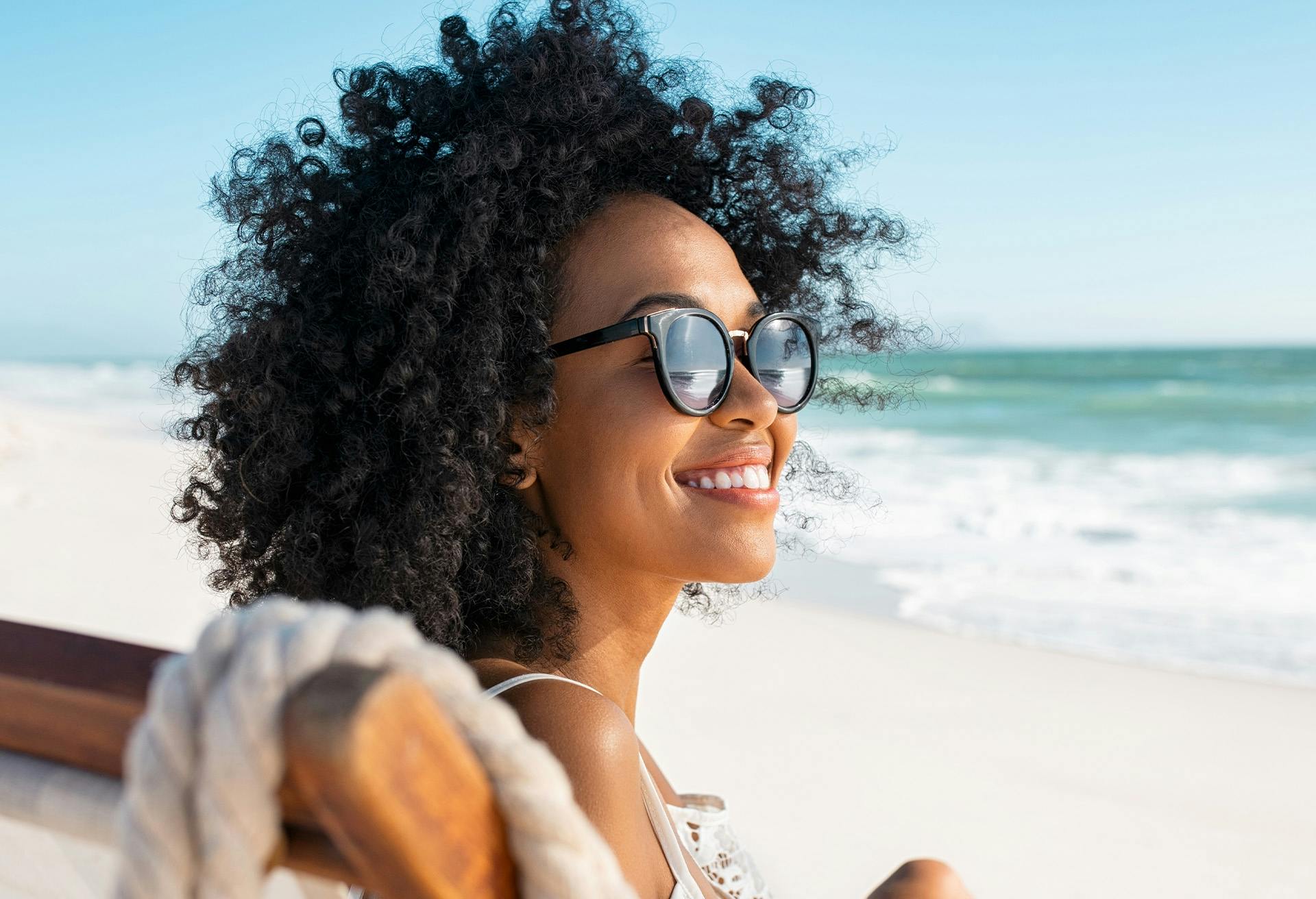 Woman with an afro smiling at the beach