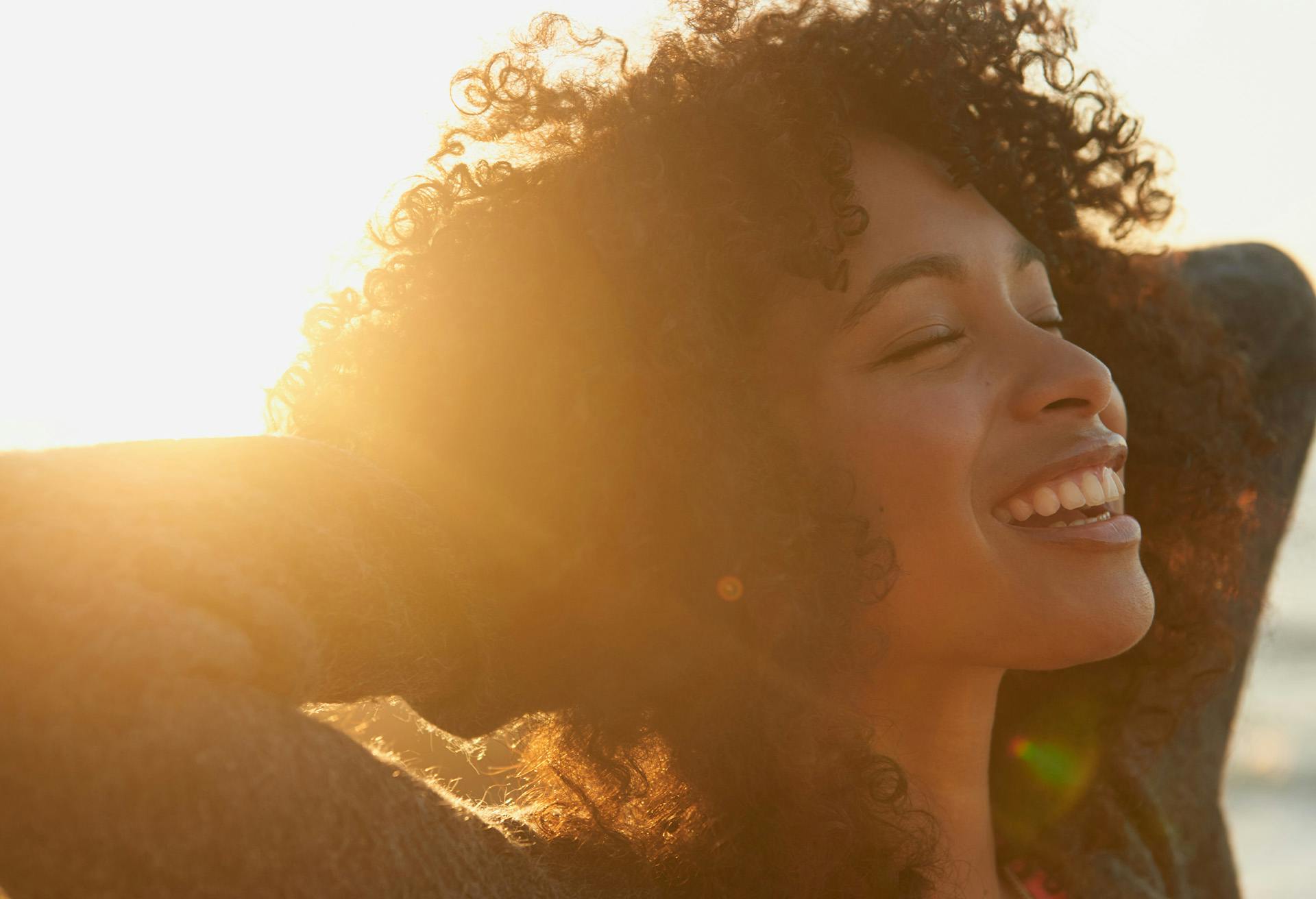 Woman smiling outside with the sun setting behind her