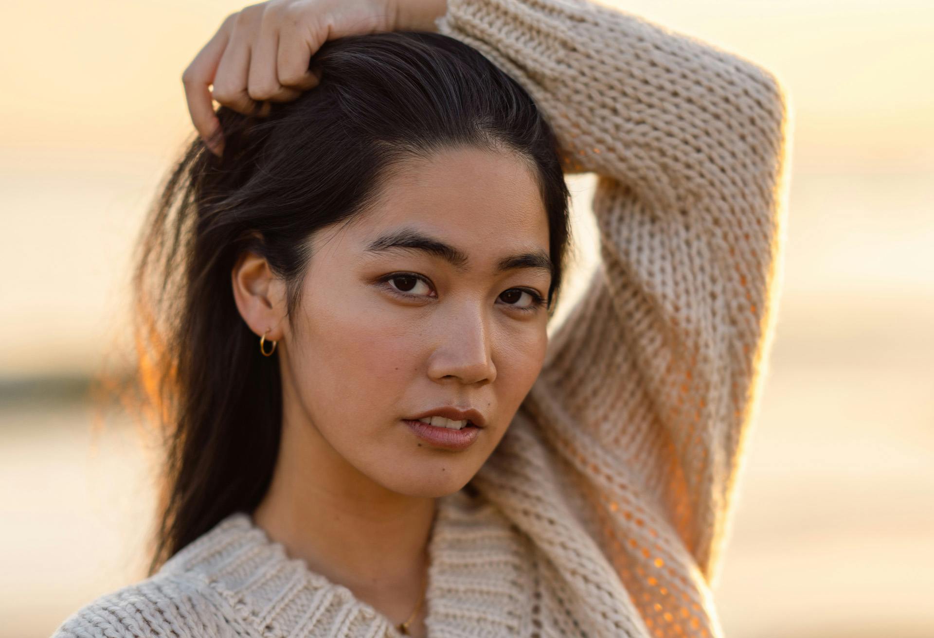 Woman with dark hair wearing a cream colored sweater