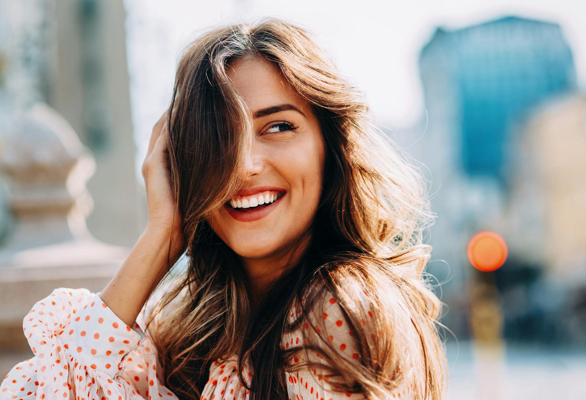 Woman with long brown hair smiling outside