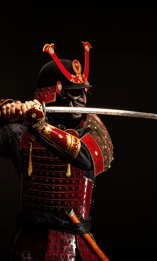 Samurai Armor A person dressed in traditional red samurai armor holds a katana with both hands, poised to strike, against a dark background.