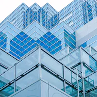 Historic and Contemporary Architecture A modern building with a glass facade and a geometric design, featuring overlapping layers of reflective blue glass panels. The structure showcases a blend of angles and lines, creating a dynamic and intricate architectural pattern against the sky.