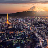 Tokyo Tower and Mount Fuji at dusk Tokyo Tower lit in orange at dusk above central Tokyo, with Mount Fuji under an orange sunset sky in the background