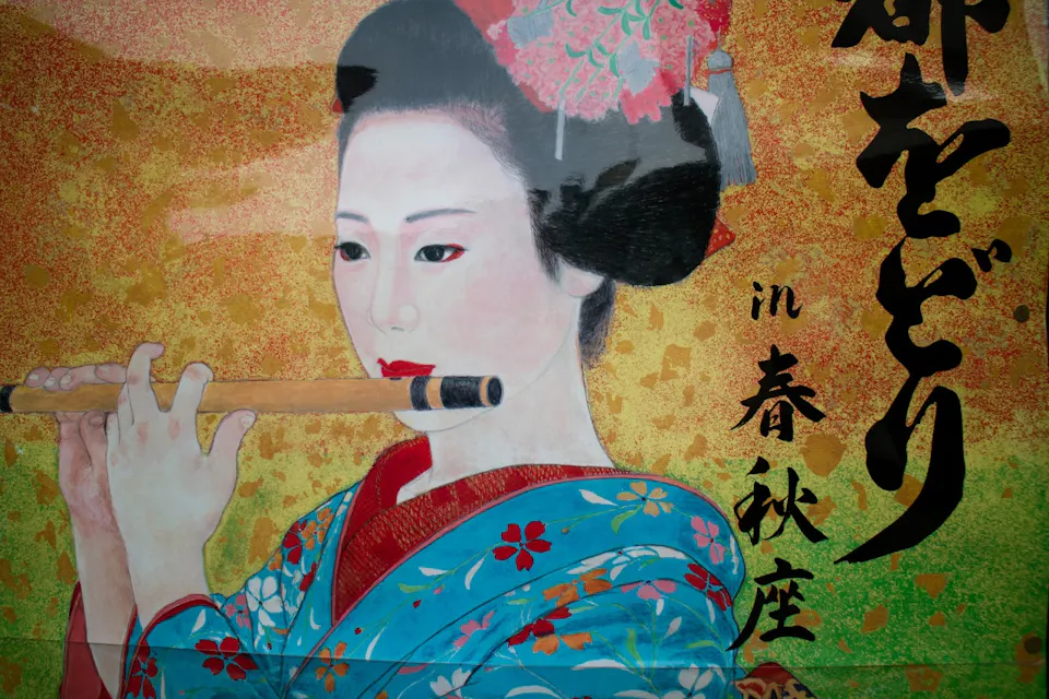 A painting of a traditional Japanese woman dressed in a vibrant blue and red floral kimono with a floral hairpiece. She is playing a bamboo flute. The background features gold and green hues with Japanese calligraphy on the right side.