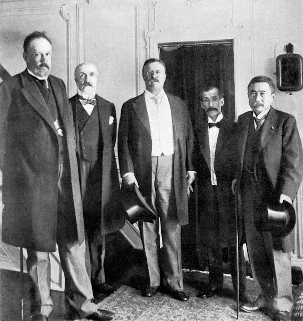 A black and white image of Theodore Roosevelt (center) with peace envoys from Russia and Japan, signing the Treaty of Portsmouth in 1905.