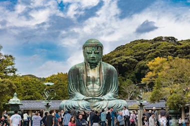 A majestic Buddha statue stands before a crowd with a cloudy sky at back, symbolizing serenity and spirituality at the Kotokuin Temple in Kamakura City, Japan.