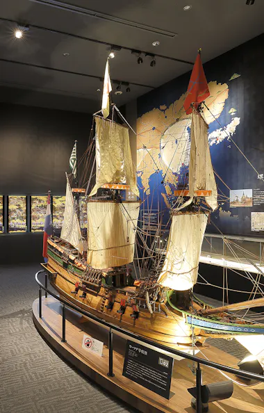 Sakai Plaza of Rikyu and Akiko A museum exhibit room featuring a large detailed model of a historic sailing ship, information panels, illuminated displays, and a world map mural on the wall.