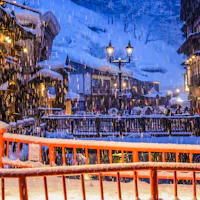 Ginzan Onsen in Yamagata limits day visitors in winter with timed entry and shuttle buses. Snow falling at night on the wooden ryokan and gas lamps lining the river in Ginzan Onsen, Yamagata