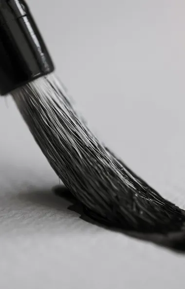 Calligraphy Workshop A close-up of a paintbrush applying black paint to textured white paper, with soft lighting in the background.