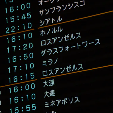 Airport A digital airport departures board displays flight times and destinations in Japanese and English, including cities like Seattle, Los Angeles, and Dallas-Fort Worth, with times listed in a green font on a black background.