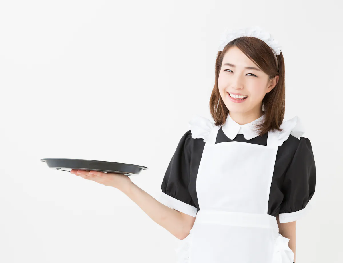 Maid Cafe A smiling woman dressed in a black and white maid uniform holds an empty serving tray in one hand against a plain white background.