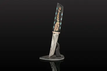 A decorative knife with an intricately patterned blade and a handle featuring colorful, artistic inlays, displayed upright in a black, curved stand against a dark background.