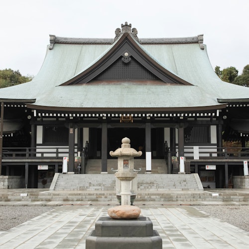 Hattasan Soneiji Temple A traditional Japanese temple with a large, sloped roof, wooden beams, and a stone lantern in front, surrounded by trees and a paved courtyard.