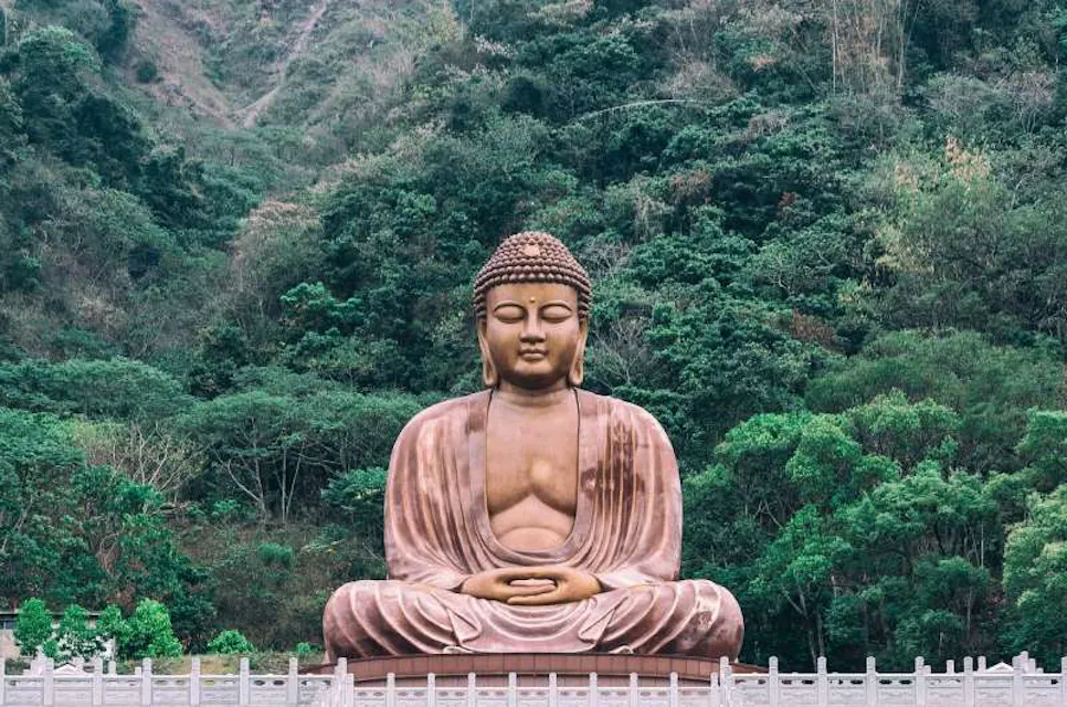 A serene Buddha statue amidst a lush green forest, creating a peaceful and harmonious ambiance