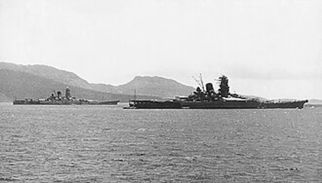 Anchored off a Micronesian island, an old black and white photo shows two Japanese battleships.