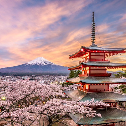 Mt. Fuji from Tokyo A five-story pagoda stands amid cherry blossoms, with Mount Fuji in the background under a vibrant sunset sky. The scene captures the serene beauty of the Japanese landscape in spring.