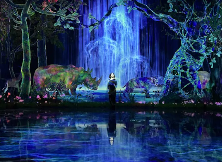 A person stands on a reflective surface in a vibrant, digitally artistic forest scene with a glowing blue waterfall. Surrounding them are digital images of a rhino and a tiger amidst illuminated trees and foliage.