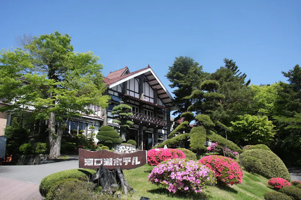 A traditional Japanese-style hotel surrounded by lush greenery and colorful flowers