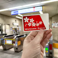 Tourist holds a welcome Suica transport card in a bustling subway station in Japan Tourist holds a welcome Suica transport card in a bustling subway station in Japan