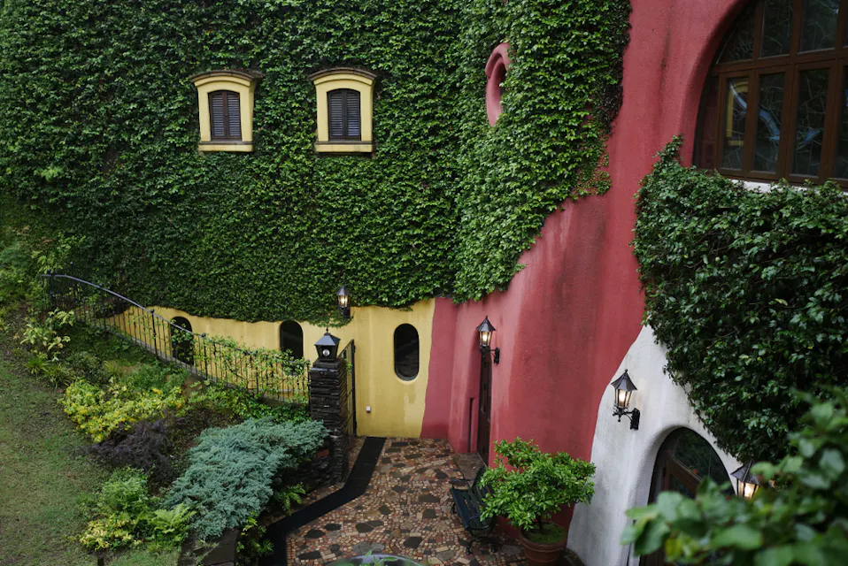 The Ghibli Museum in Mitaka sells tickets only in advance. The ivy-covered pink and yellow walls of the Ghibli Museum in Mitaka, with round windows set into the facade