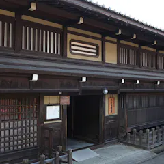 Kusakabe Folk Museum A traditional Japanese wooden building with sliding lattice doors, wooden railings, and a tiled roof, situated on a quiet street.