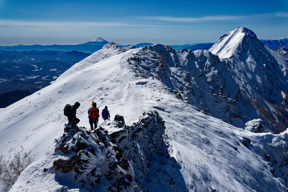 Climbers walking along the Yokodake ridgeline of the Yatsugatake mountain range in midwinter, with a view of Mount Fuji and Akadake